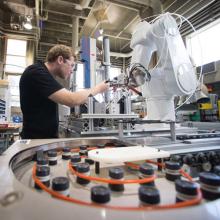 Student works with robotic arm in the MILL